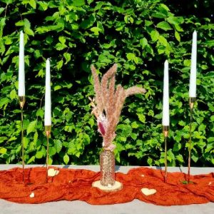 4 goldene Kerzenständer mit rosaner Vase